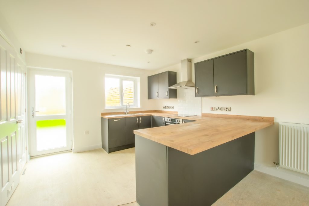 new kitchen in new build home with dark grey units and wooden worktops