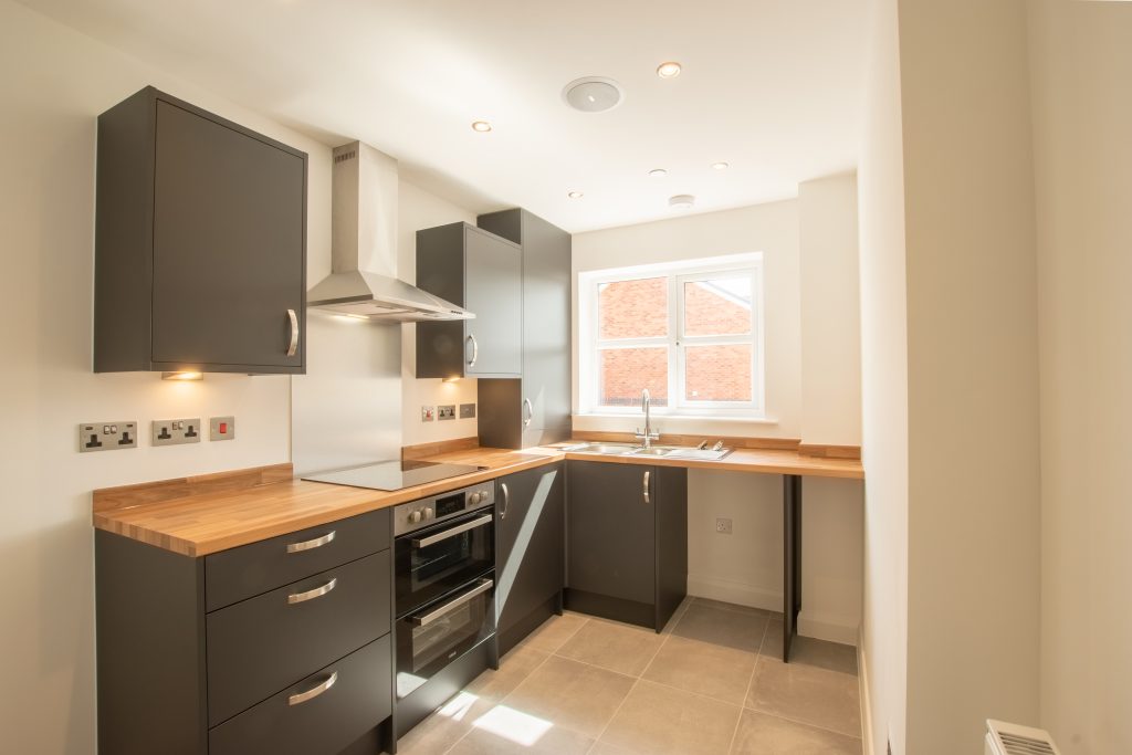 small kitchen with grey units and wooden worktop in bew build property