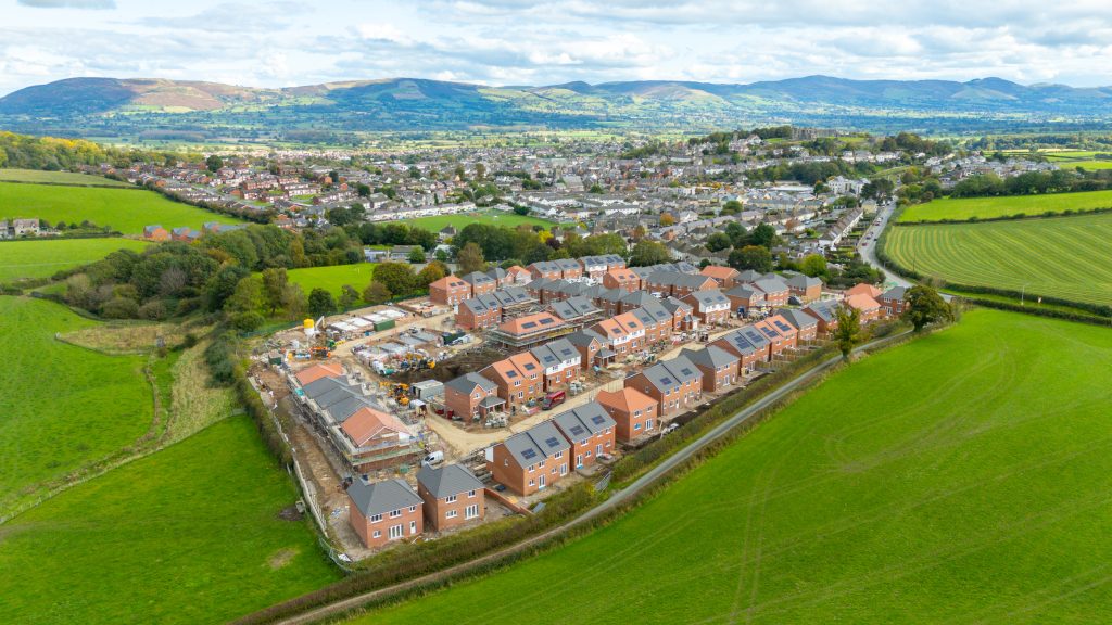 A development of new houses with the town of Denbigh in the background.