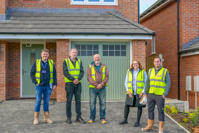 Adra officers with Councillors from Denbighshire Council outside a house with a garage. 