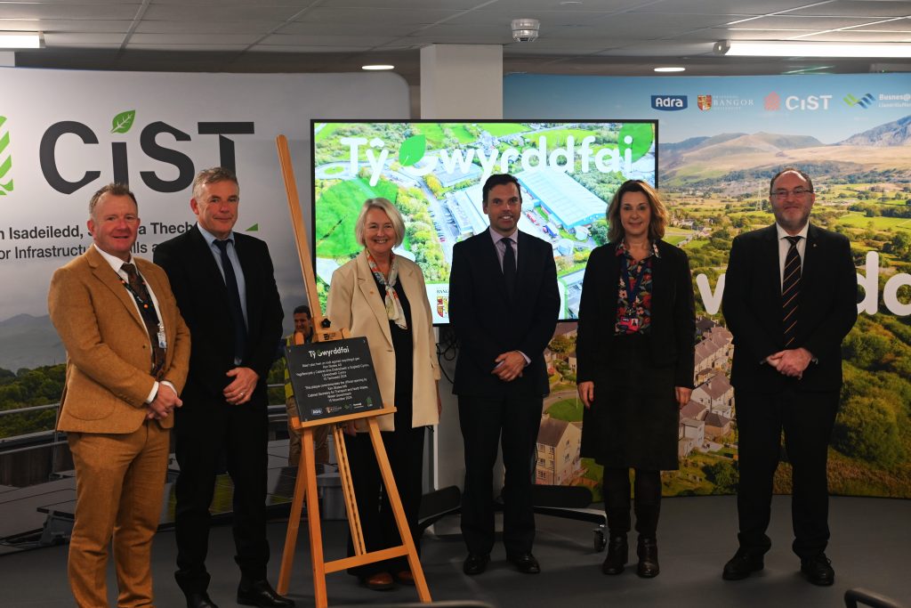 Photo of Ken Skates AM with a plaque marking the opening of Tŷ Gwyrddfai.